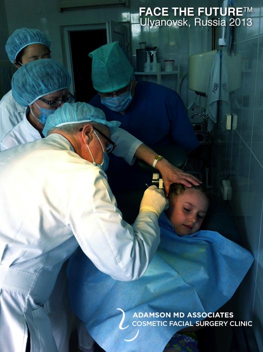 Dr. Peter A. Adamson, Toronto Facial Plastic Surgeon, examines a young girl on a Face The Future Mission